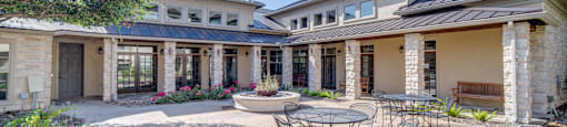 a patio with a table and chairs in front of a house