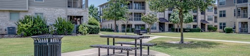 a picnic area with a trash can in front of an apartment building