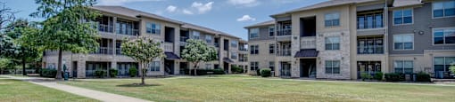 an apartment building with a green lawn and sidewalk