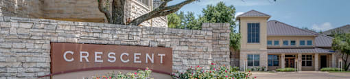 a sign for the crescent building in front of a sidewalk and plants