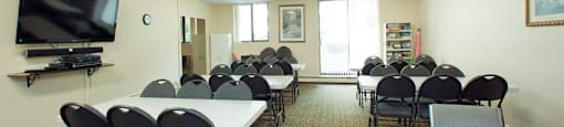 Wellington Park Towers social room with tables and chair and tv in St. Thomas, ON