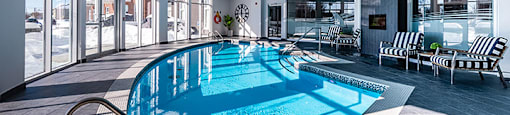 Curved indoor pool with floor to ceiling windows at La Voile Broisbriand apartments in Broisbriand, Quebec