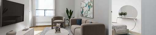 A modern living room with a flat screen TV, a coffee table, and a comfortable sofa.