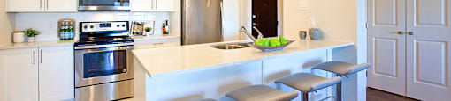 Amesbury Gate Kitchen with four stools beside the stone counter top in Bedford, NS
