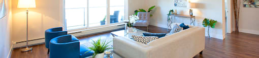 Amesbury Gate Living room with glass end table between a blue chair and white couch in Bedford, NS