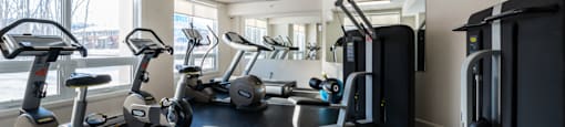 Brightly lit, fully equipped fitness centre at Axial Towers apartment in Laval, Quebec