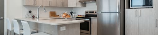 Modern kitchen with stainless steel appliances at Axial Towers apartment in Laval, Quebec