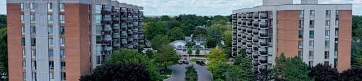 a city street with two apartment buildings on either side and trees in the background