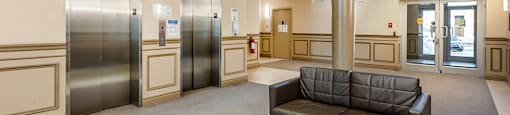 Bourg du Village lobby with seating area and elevator doors in Sainte Therese, QC