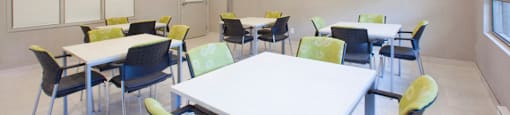 Brighton Court social room with tables, chairs and TV in Windsor, ON