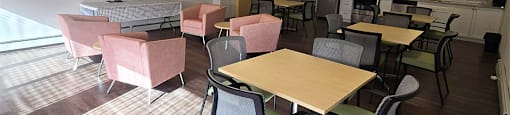 Social room with couch, tables, chairs, and stainless steel appliances at Brockville Apartments in Brockville, ON