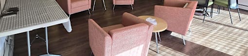 Social room with couch, tables, chairs, and stainless steel appliances at Brockville Apartments in Brockville, ON