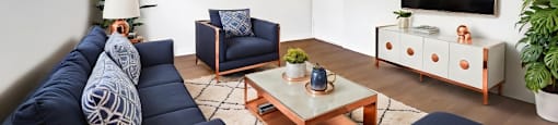 A living room with a blue sofa, a wooden coffee table, and a painting on the wall.