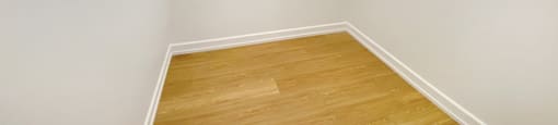 A corner of a room with wooden flooring.