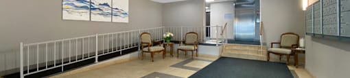 A hallway with a blue carpet and chairs on the side.