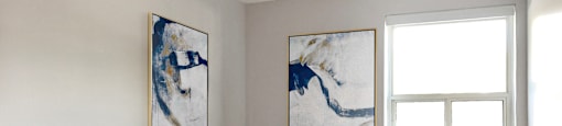 a bedroom with a bed and two paintings on the wall