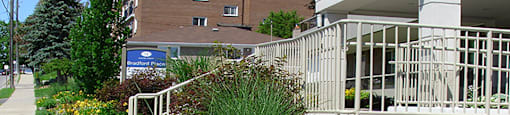 Garden with bright yellow flowers next to the main entry at Bradford Place Apartments in Bradford, ON