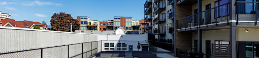 A rooftop garden with grey planters and a black fence at The Ambrosi in Kelowna, BC.