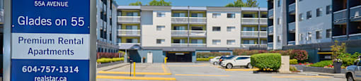 a sign for the glades on 55 apartments sits in front of a parking lot