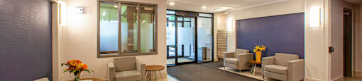 Sunnidale Place in Barrie, ON lobby with four club chairs and side tables, looking towards office and main building entrance