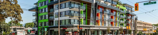 A street view of a multi-story building with a green and orange facade at 388 Kaslo East Village Apartments.