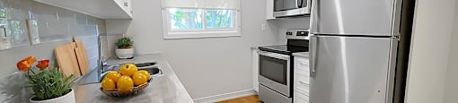 A kitchen with a refrigerator, oven, and sink.