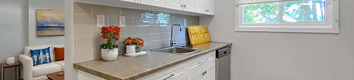 A kitchen with white cabinets and a wooden floor.