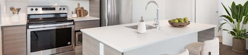 A modern kitchen with a white island and stainless steel appliances at 388 Kaslo East Village.