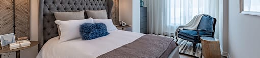 Large modern bedroom with custom window treatments at La Voile Pointe-Claire apartments in Pointe-Claire, Quebec