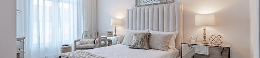 Spacious, modern bedroom with mirrored nightstand at La Voile Pointe-Claire apartments in Pointe-Claire, Quebec