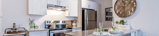 Modern kitchen with stainless steele appliances and quartz countertops at La Voile Pointe-Claire apartments