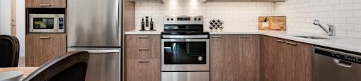 Open-concept kitchen with stainless steel appliances at Le Saint-Laurent Apartments in Brossard
