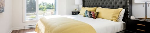 Primary bedroom with large window and blinds included at Le Saint-Laurent Apartments in Brossard