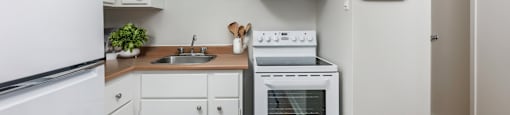 a kitchen with white appliances and white cabinets at Les Jardins Hauterives