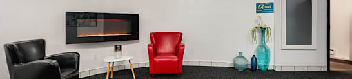 a living room with black carpet and red chairs and a television