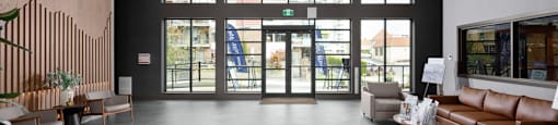 A spacious lobby with a wooden ceiling and a large glass door at The Ambrosi in Kelowna, BC.