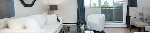 Living room area in an open-concept layout, looking towards sliding glass patio door at Lorneville Apartments in Cornwall, ON