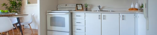 Kitchen with white appliances and white cabinets in a standard suite at Lorneville Apartments in Cornwall, ON