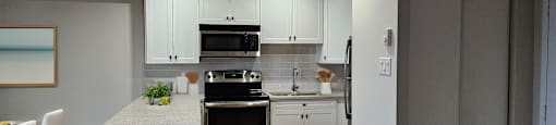 a kitchen and dining room with white cabinets and stainless steel appliances at Lorneville Apartments in Cornwall Ontario