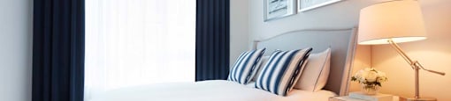 A bedroom with a large bed, a nightstand with a lamp, and pictures on the wall.