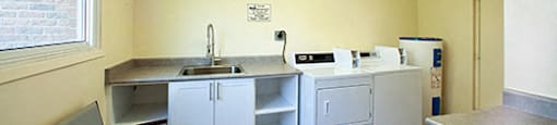 A kitchen with a sink, cabinets, and a chair.