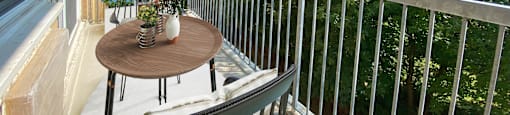 A balcony with a table and chairs overlooking a green tree.