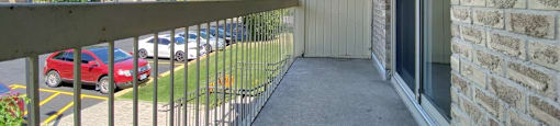 A private balcony with a metal railing overlooks a parking lot at Moira Apartments in Belleville, ON