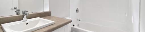 A bright bathroom with a sink, toilet and bathtub at Moira Apartments in Belleville, ON