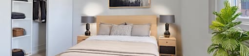 A bedroom with a large bed, a ceiling fan, and a potted plant at Moira Apartments in Belleville, ON