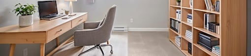 A bedroom set up as a home office with a desk, chair, and bookshelf at Moira Apartments in Belleville, ON