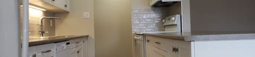 Refinished kitchen, showing storage island, in a refinished kitchen in an open concept layout at Moira Apartments in Belleville, ON.