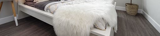 Bed with fluffy white throw blanket at the foot of the bed