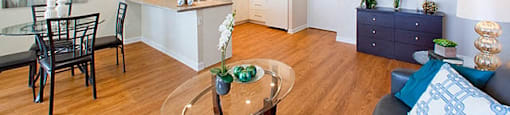 Edgehill Apartments in Barrie, ON Open concept room with sleek dinner table, kitchen, coffee table, couch and drawers.