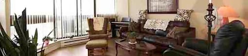 Prince William Apartments spacious living room with large window and balcony access in Bellville, ON